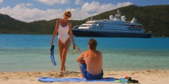 Man and woman on beach with cruise ship in background