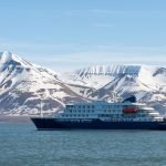 an expedition cruise ship with a backdrop of snow-capped mountains